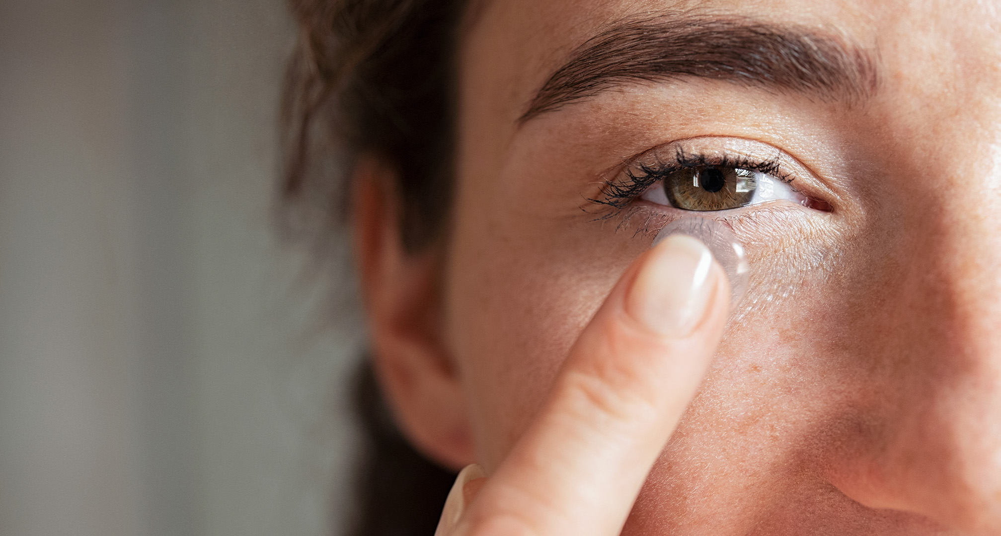 närbild av en person som håller en kontaktlins framför ögat