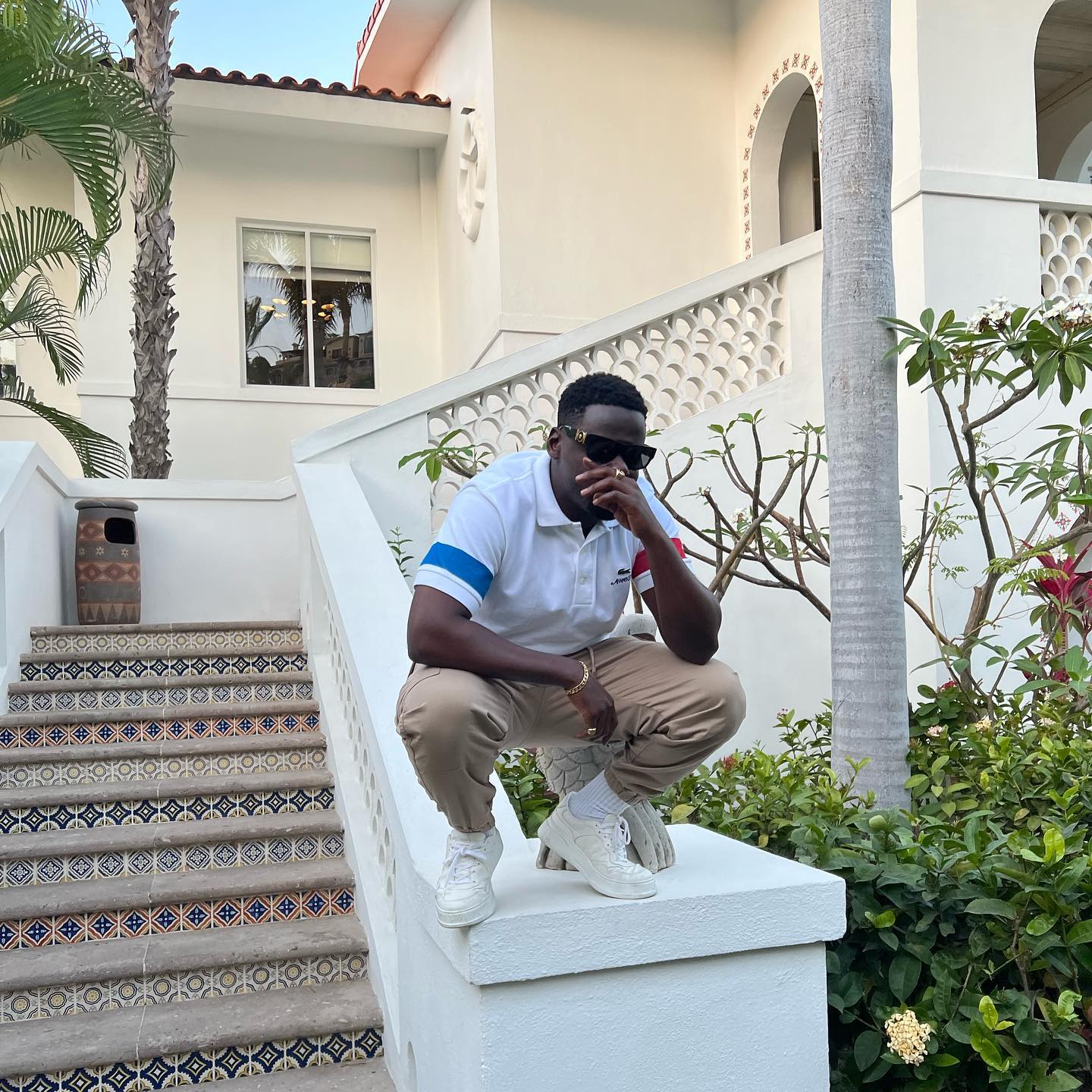 Daniel Kaluuya på huk på en trappa med svarta solglasögon
