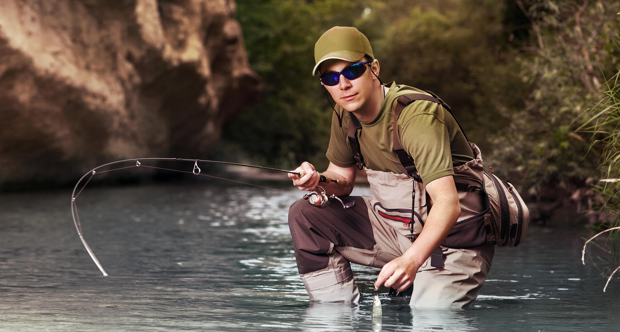 en fiskare på knä i vatten som bär solglasögon