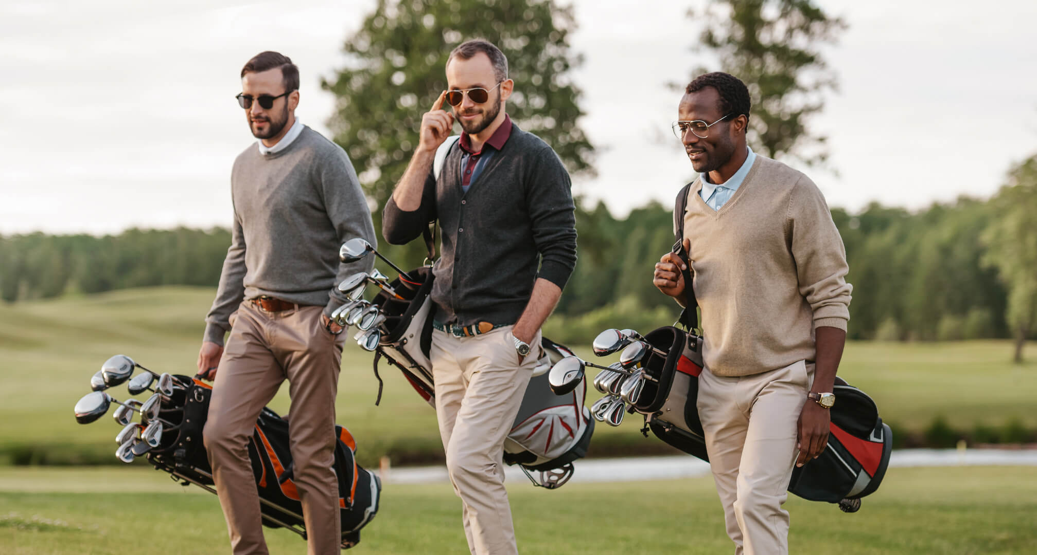 tre personer som spelar golf med solglasögon och golfbagar