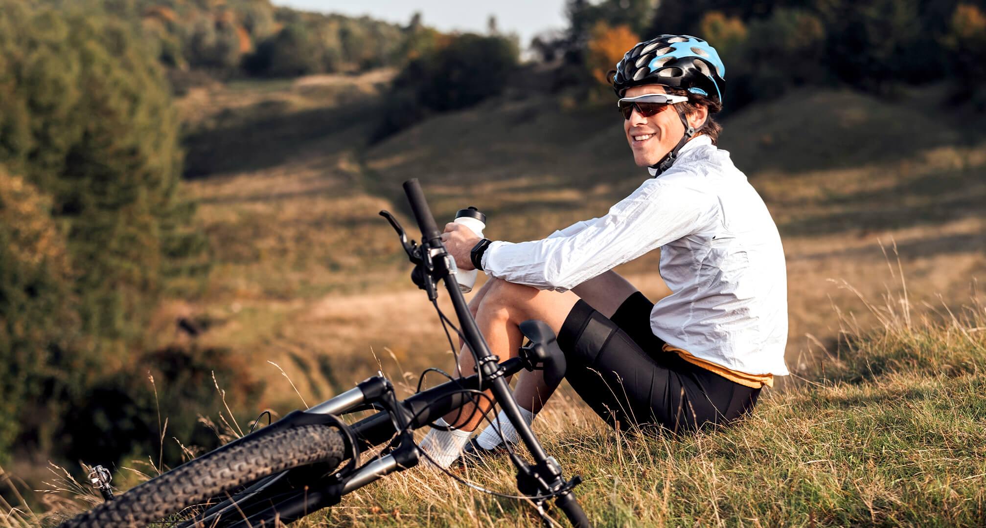 person sitter på en kulle med en mountainbike och bär solglasögon